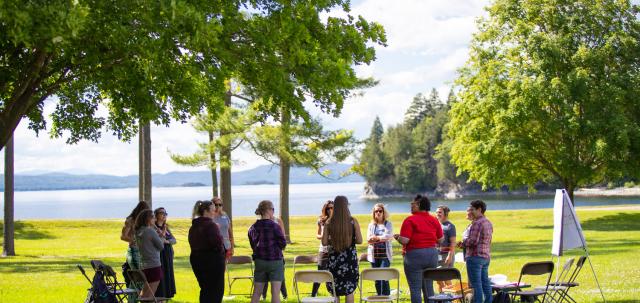 Educators gathered on the Coach Barn lawn, Lake Champlain in the background.